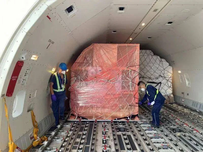 Workers loading large cargo inside a freighter aircraft