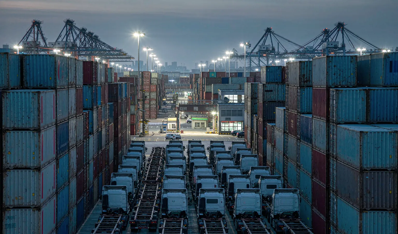 Crowded container yard at dusk with stacked containers and queued trucks - global port congestion in late 2026, CargoSolid freight update
