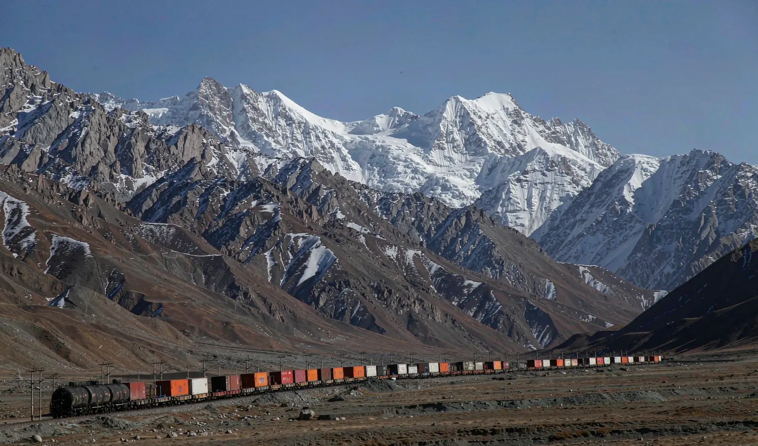 Freight train with containers crossing a high Central Asian mountain pass - China to Uzbekistan rail routes by CargoSolid