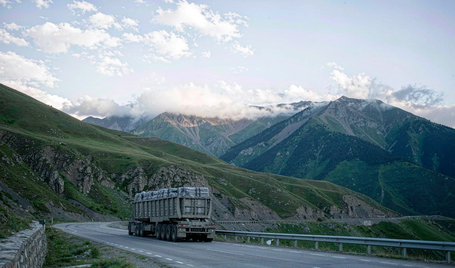 Container truck driving on a highway through green Caucasus foothills - inland delivery in Georgia by CargoSolid