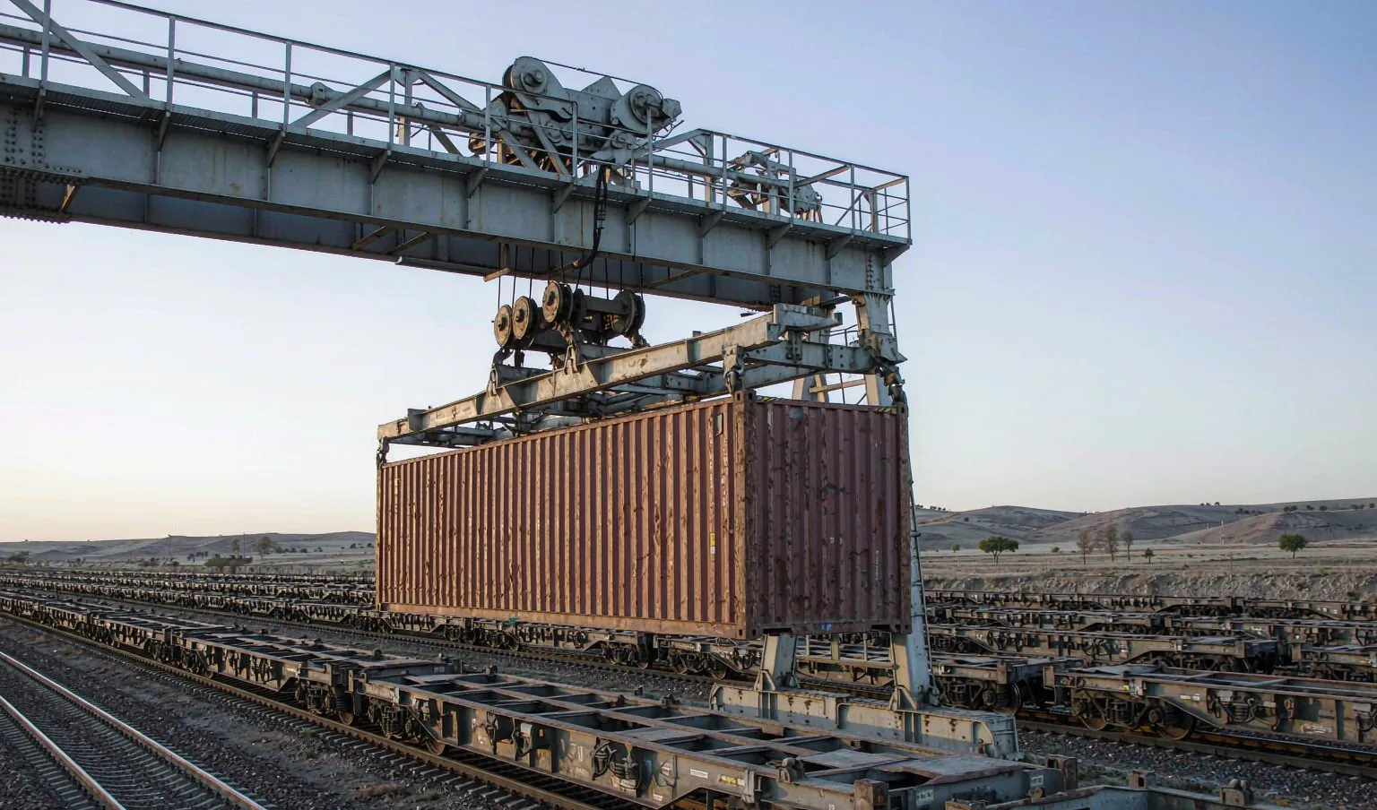 Gantry crane lifting a container at a rail gauge-change border yard - China-Europe rail freight by CargoSolid